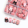 A box of pink and white leopard print press-on nails with various bow designs.