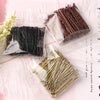 A collection of metal U-shaped hair pins in various shades, including black, copper, and gold, displayed on white feathers.