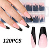 A hand holds a clear plastic box filled with 120 sets of nude pink matte French press on nails and several loose nails.