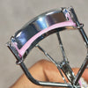 A close-up of a professional eyelash curler set with silver metal and pink silicone pads.