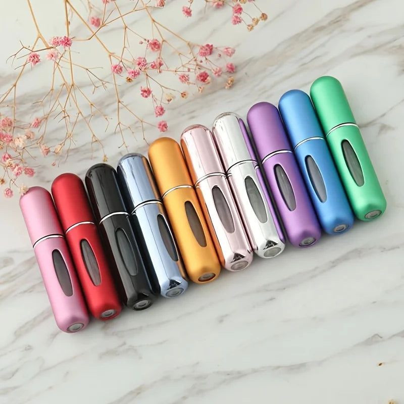 A row of colorful mini refillable perfume atomizer bottles arranged diagonally on a white marble surface.