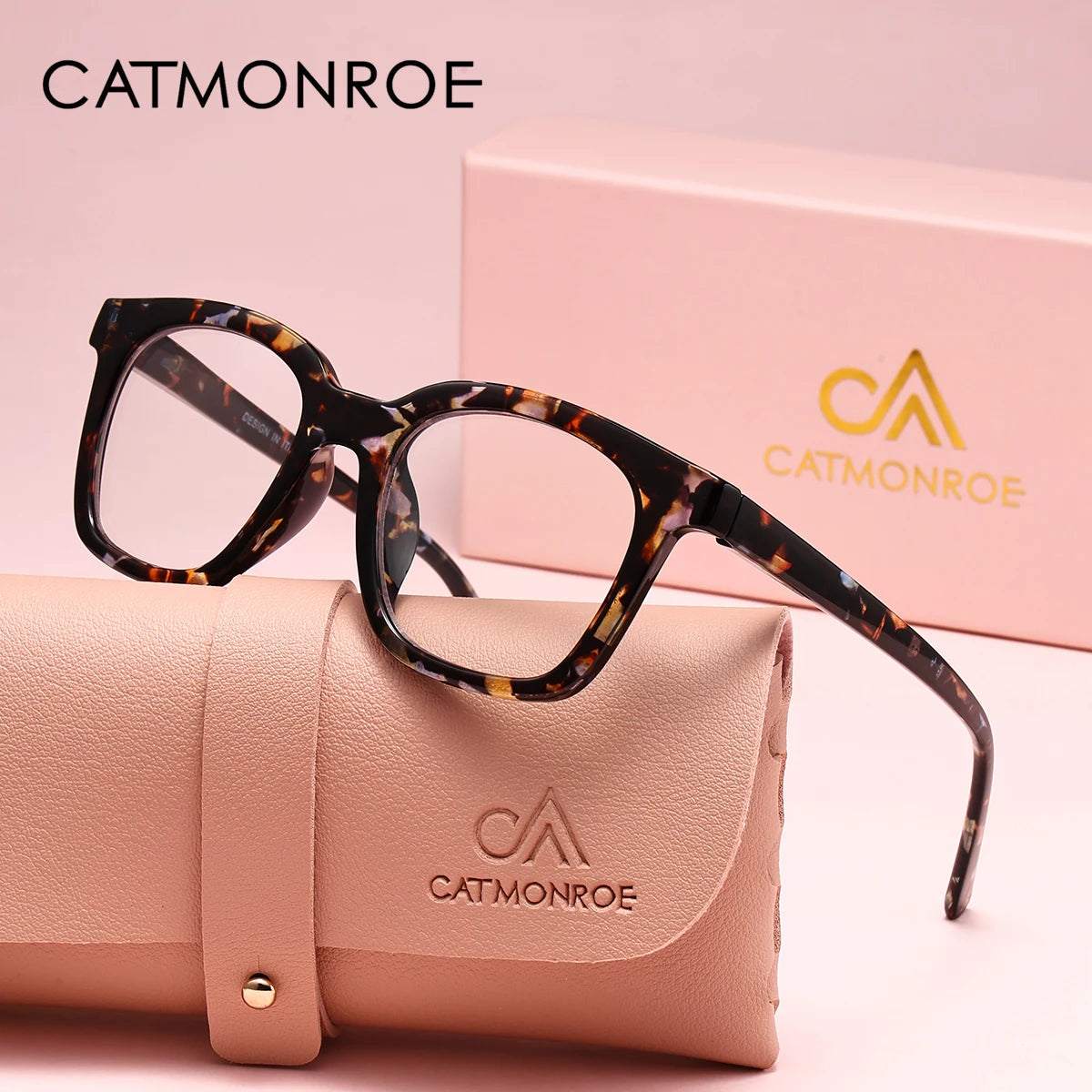 A pair of black-framed square reading glasses with a leopard print pattern resting on a pink leather clutch.
