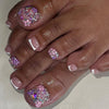 A hand displaying press-on fake nails with short square French design featuring pink and purple glitter accents.