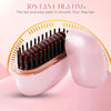 A pink portable mini hair straightener with a gold-toned heating plate and a white casing is shown on a pink background.