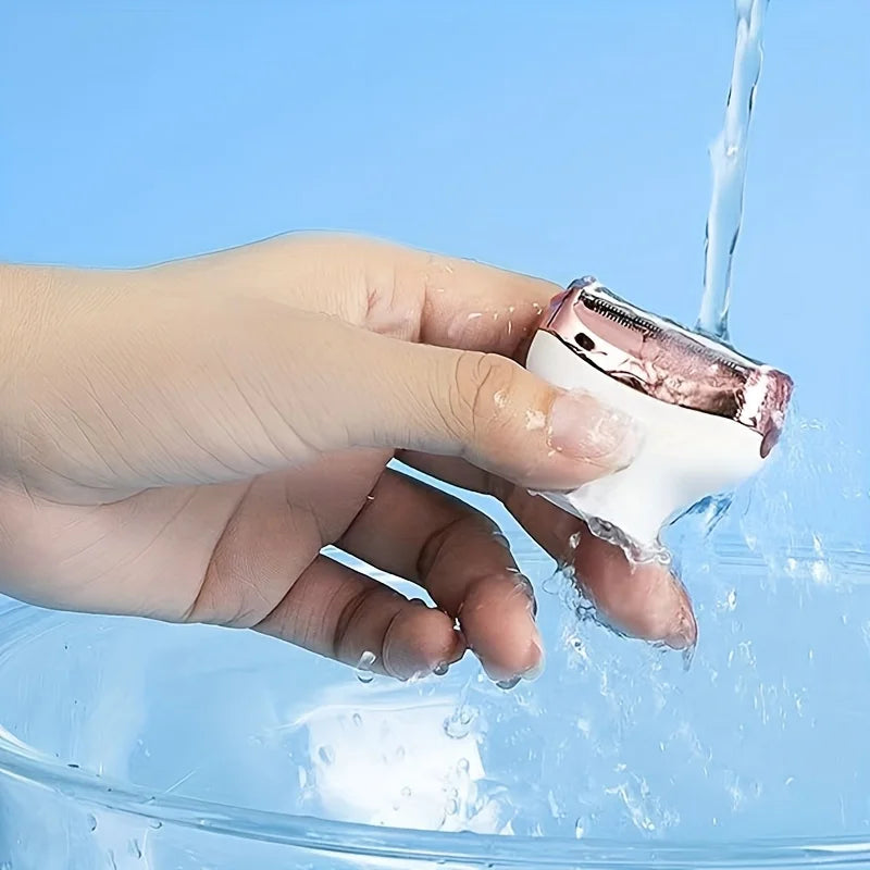 A hand is using a 4-in-1 electric body hair removal shaver, which is being rinsed under running water.