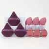 A set of twelve all-purpose makeup sponges in various shades of pink and purple, arranged on a white surface.