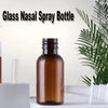 Reusable amber glass nasal spray bottles displayed on a white surface with a green plant in the background.
