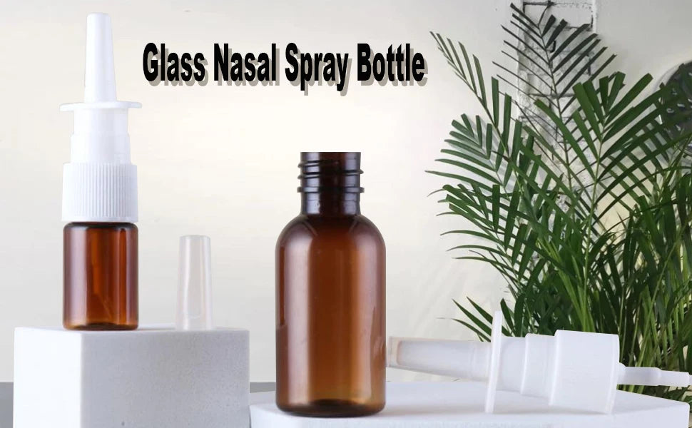Reusable amber glass nasal spray bottles displayed on a white surface with a green plant in the background.