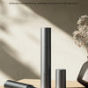 A sleek, black electric nose hair trimmer is shown standing upright next to its detachable head on a wooden surface.