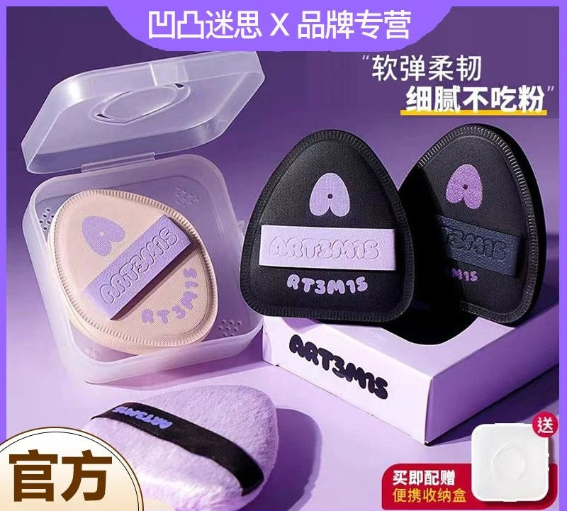 Un set de puffs cosmétiques noirs et roses flockés emballé dans une boîte transparente avec un couvercle blanc.