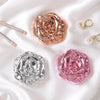 A set of vintage rose design double-sided pocket makeup mirrors in rose gold and silver on a white satin background.