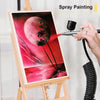 A hand is using a spray painting tool to apply pink and red paint to a canvas featuring a large pink moon and palm trees.