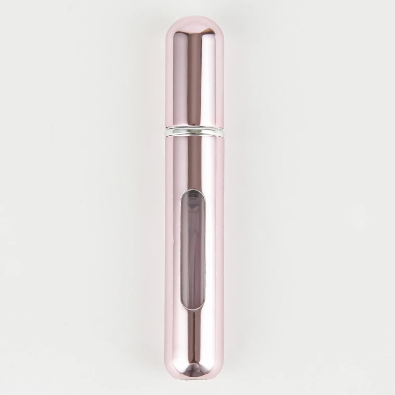 A sleek, cylindrical portable refillable perfume bottle with a rose gold finish and silver accents.