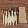 A box containing a set of ten natural bamboo toothbrushes is displayed on a wooden surface.