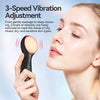 A woman is using a black facial cleansing brush with a wooden head for skin treatment.