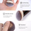 A close-up of a fluffy, gray makeup brush demonstrating contouring and dense weaving.