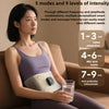 A woman is using an EMS waist pulse massager for body shaping device on her abdomen while sitting on a couch.