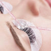Gros plan d'un œil avec une micro brosse en cristal utilisée pour les extensions de cils ou le détail.
