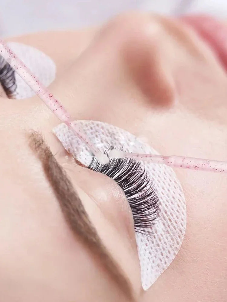 Gros plan d'un œil avec une micro brosse en cristal utilisée pour les extensions de cils ou le détail.