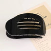A black oval flat hair clip is shown resting on a piece of lined paper.