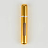A slender, cylindrical gold-colored perfume bottle with a silver band and a translucent brown liquid inside.