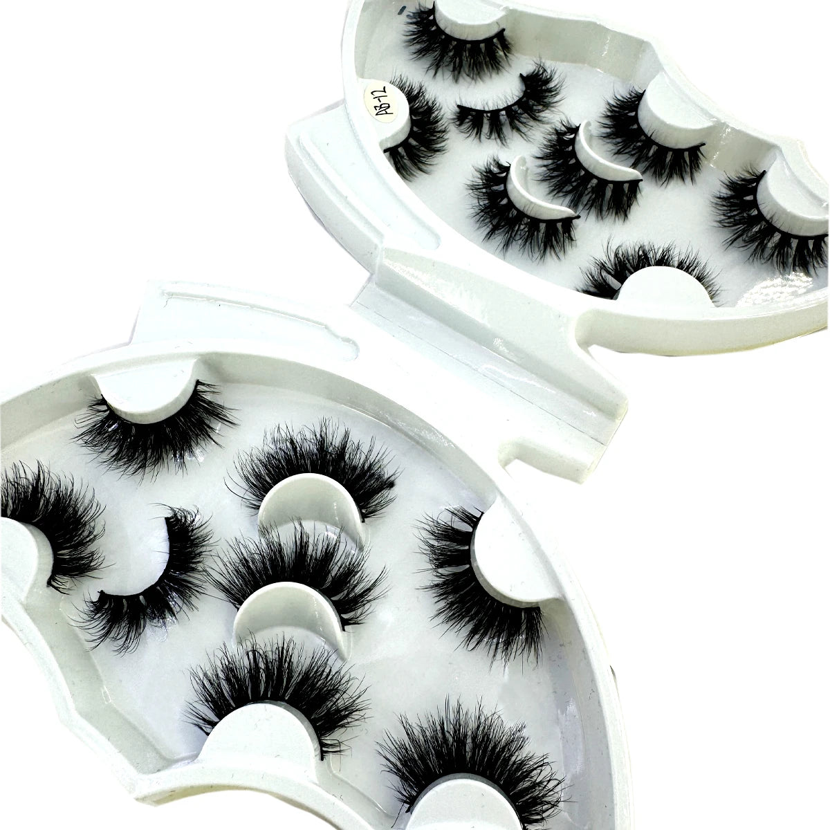 A set of natural mink striped false eyelash extensions displayed in an open white packaging.