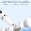 A white ultrasonic teeth cleaning tool is shown cleaning plaque and tartar from a tooth surface.