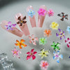 A collection of pink and translucent resin nail charms shaped like hibiscus flowers in various colors