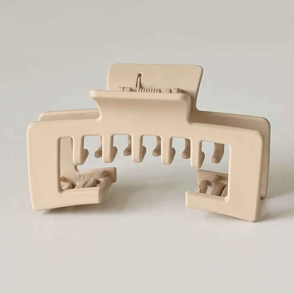 A beige non-slip hat claw clip with a strong hold design for securing baseball caps.