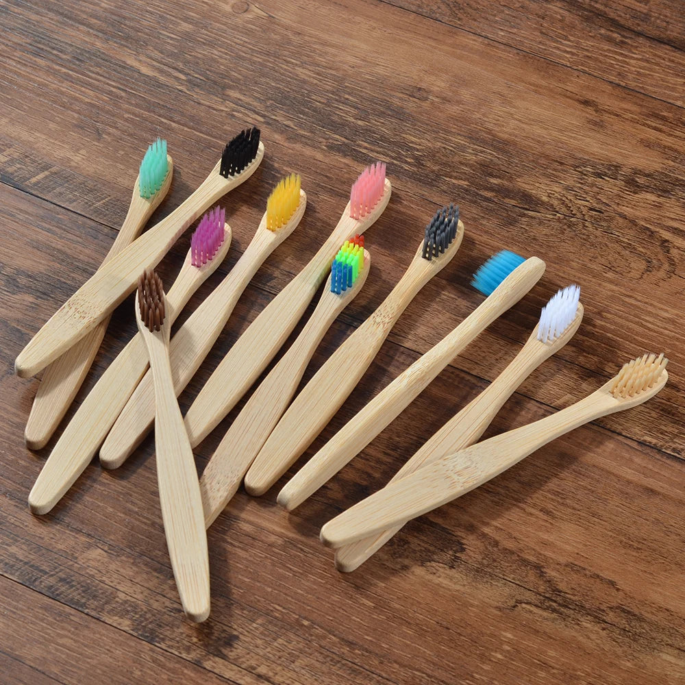 Une collection de dix brosses à dents en bambou écologiques aux poils de différentes couleurs, posées sur une surface en bois