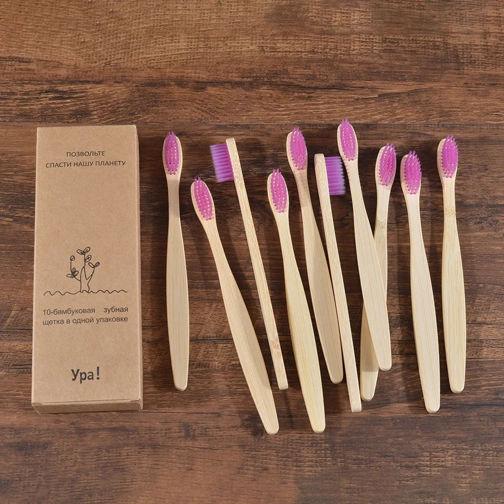 A set of ten natural bamboo toothbrushes with pink bristles arranged on a wooden surface.