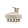 A beige silicone body and scalp massage brush with a wide base and multiple pointed tips.