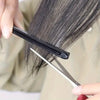 A hand uses a V-Comb hair styling tool to smooth and finish dark hair.