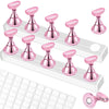 A set of pink nail practice stands with double-sided tape and a white grid mat.