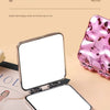 Un miroir de maquillage carré pliable ouvert à côté d'un mini-miroir rose et d'une boîte de produit cosmétique.