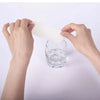 Hands are holding a white disposable wet wipe above a glass of water.