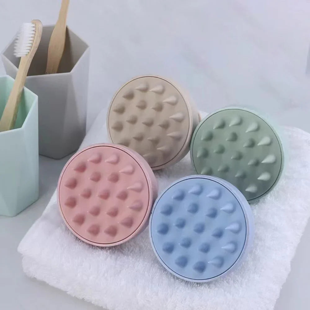 A collection of silicone scalp massage and body brushes in various pastel colors resting on a white towel.