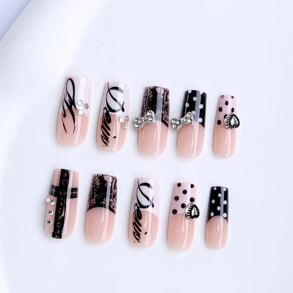 A set of gothic Y2K press-on nails featuring black and pink designs with cross and bow embellishments.