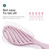 A pink hollow-out detangling hair brush with scalp massage bristles shown in a close-up view.