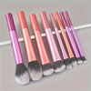 Eight makeup brushes in various shades of pink and purple displayed horizontally.