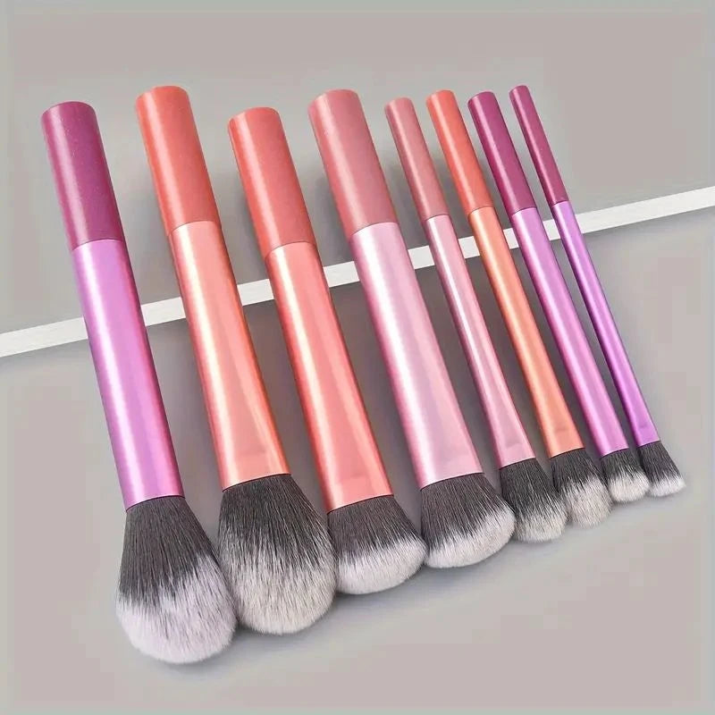Eight makeup brushes in various shades of pink and purple displayed horizontally.