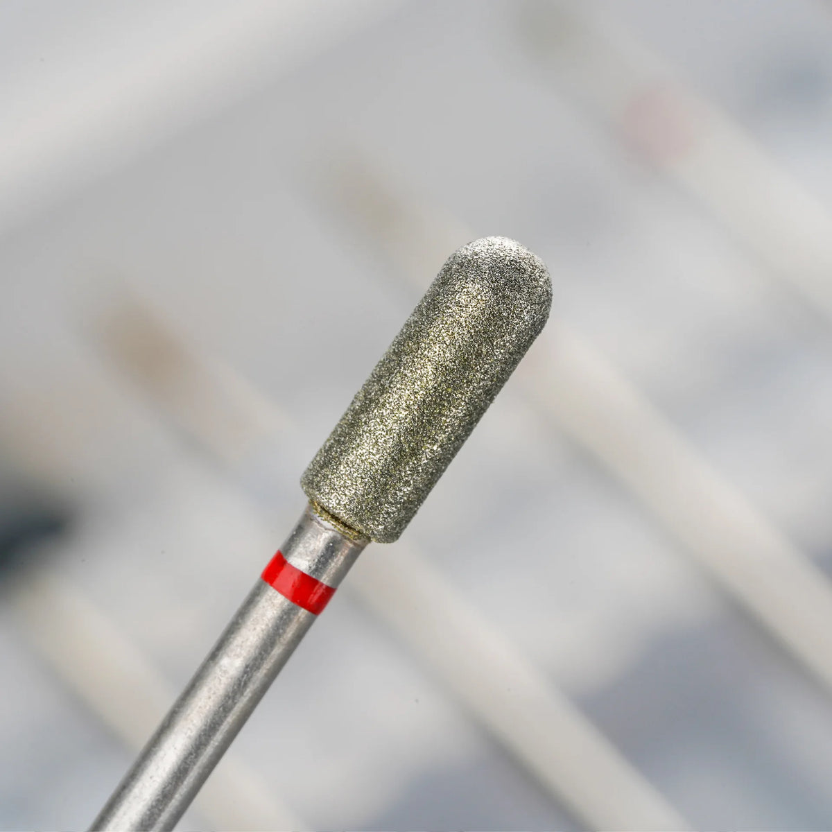 Nahaufnahme einer professionellen Diamant-Sand-Nagelfeile mit silbernem Griff und rotem Akzent.