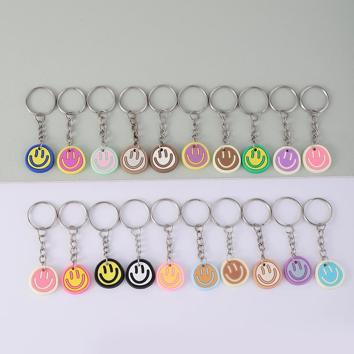 A set of 20 cartoon smile face keychains in various colors and shapes arranged in a single row.
