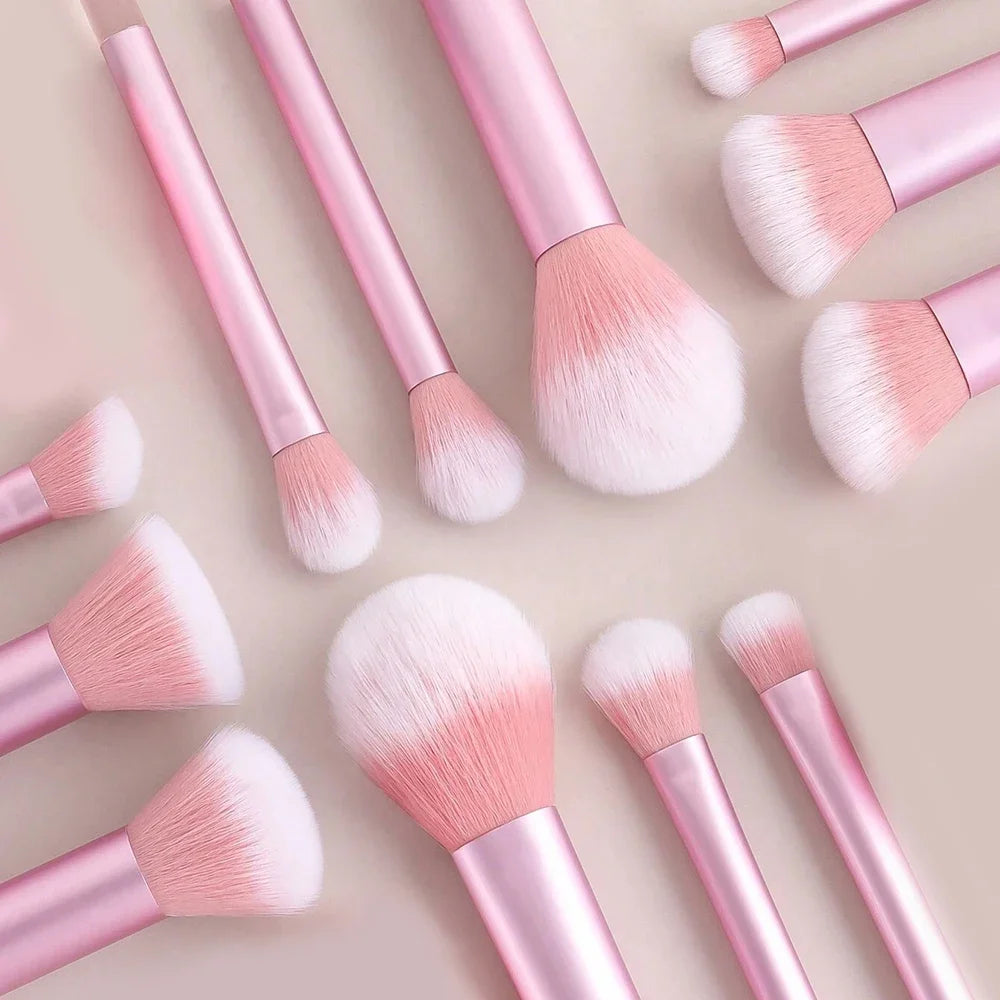A collection of pink and white makeup brushes and puffs arranged on a light background.