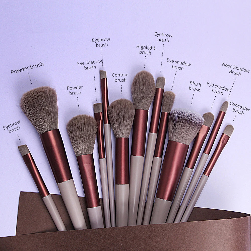 A collection of 13 professional makeup brushes, including eyebrow, powder, contour, and eyeshadow brushes, displayed on a lig
