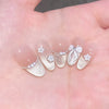 A hand displays 24 pink flower almond press on nails with pearl and white floral accents.