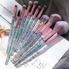 A set of ten professional makeup brushes with iridescent pink and green bristles displayed on a white surface.