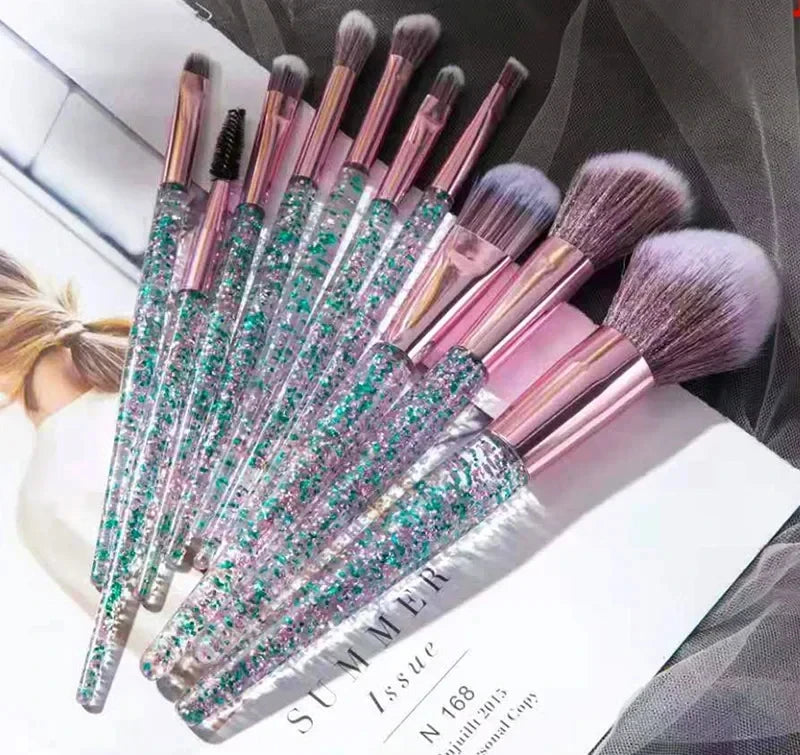 A set of ten professional makeup brushes with iridescent pink and green bristles displayed on a white surface.