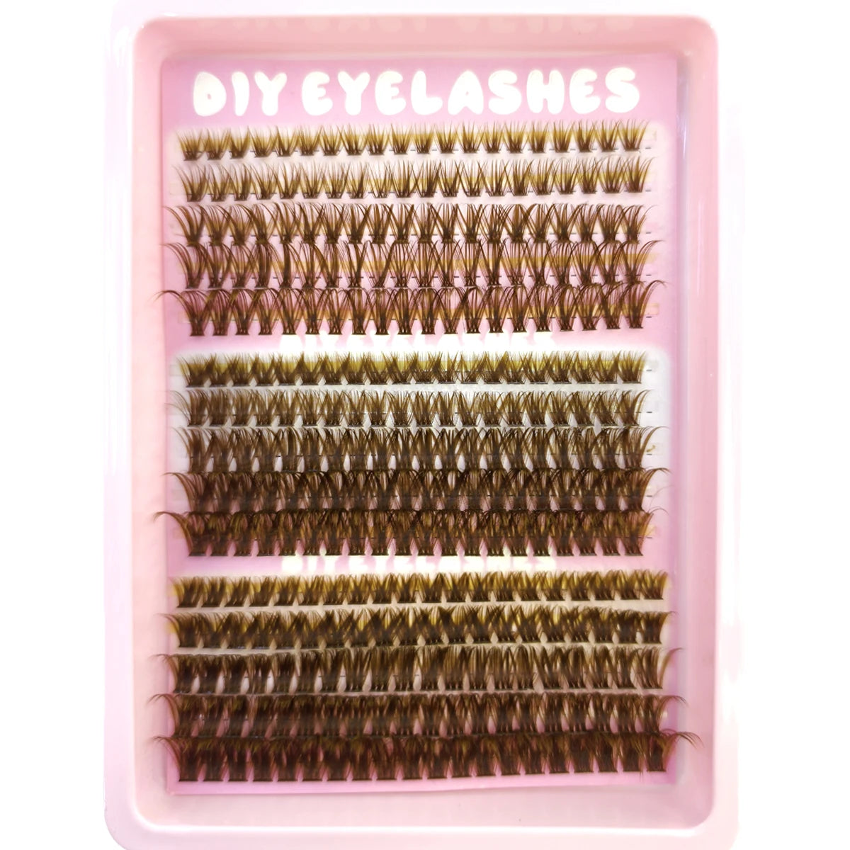 Un plateau rose contenant diverses extensions de faux cils naturels et fins, dans différentes nuances de brun et d'or.