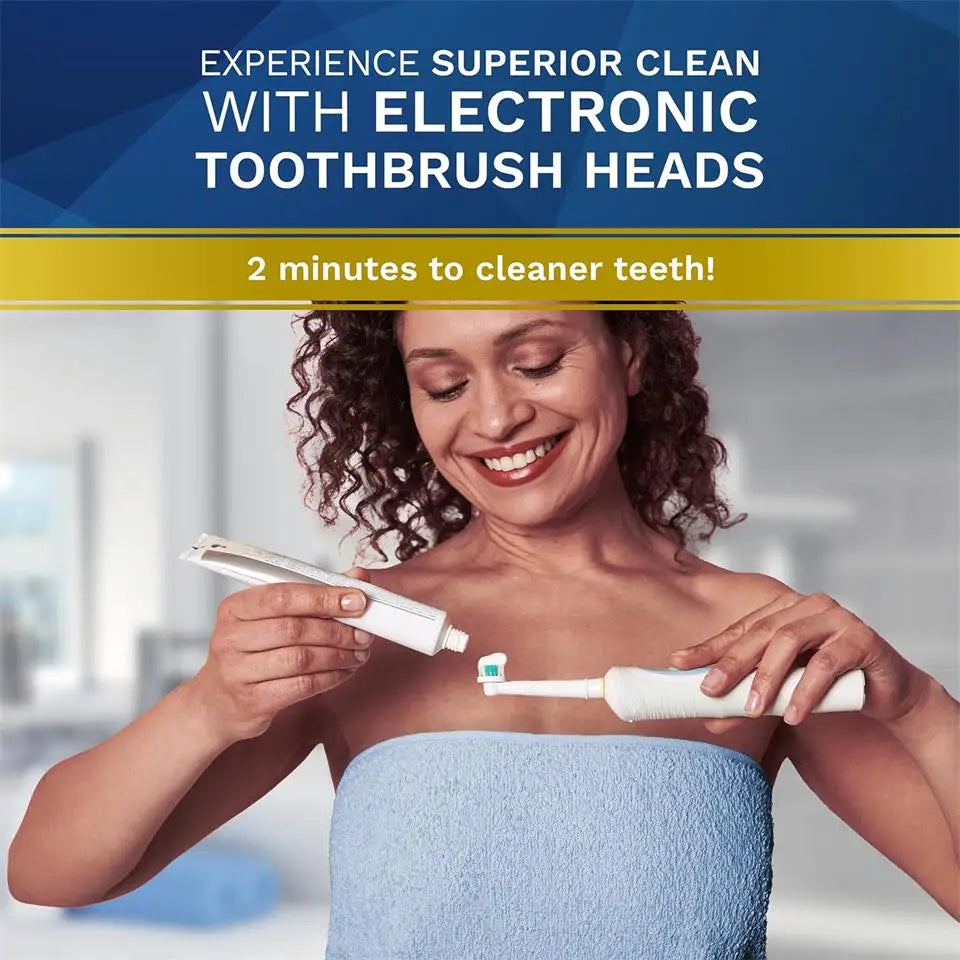 A woman is using an electronic toothbrush head on her teeth in a bright, modern setting.